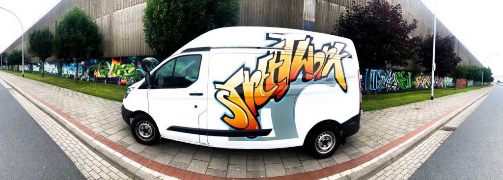 Weißer Bus mit Graffiti Streetwork draußen vor besprühten Wänden 